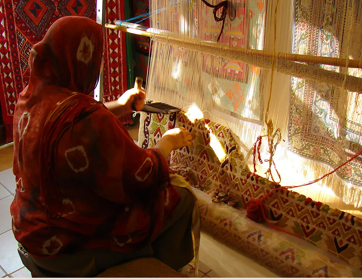 A weaver working at a traditional carpet loom